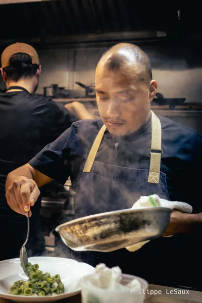A cook puts the finishing touches on a green pasta dish