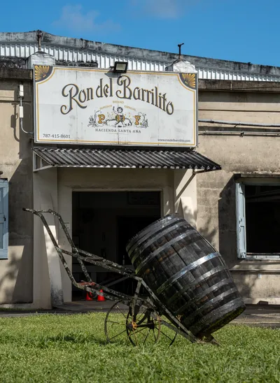 The entrance to Ron del Barrilito distillery with a vintage barrel and cart sculpture