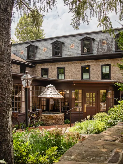 A stone and wood inn exterior with a gas lantern and lush garden courtyard