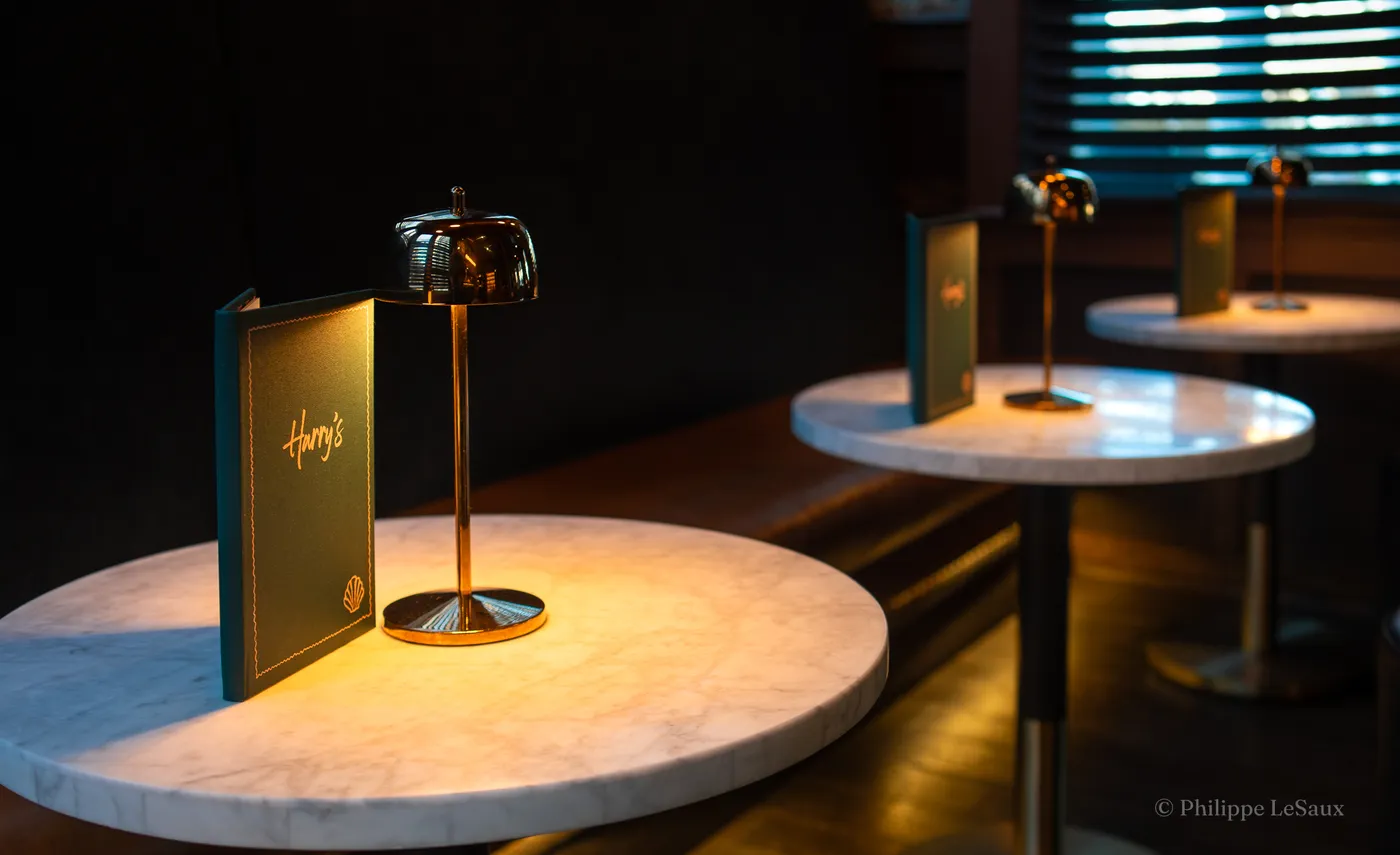 Marble bistro tables lit by small gold lamps inside Harry's restaurant