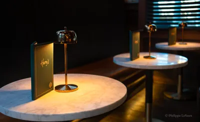 Marble bistro tables lit by small gold lamps inside Harry's restaurant