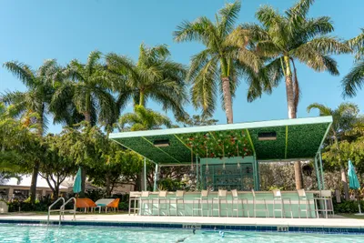A poolside bar surrounded by palm trees on a sunny day